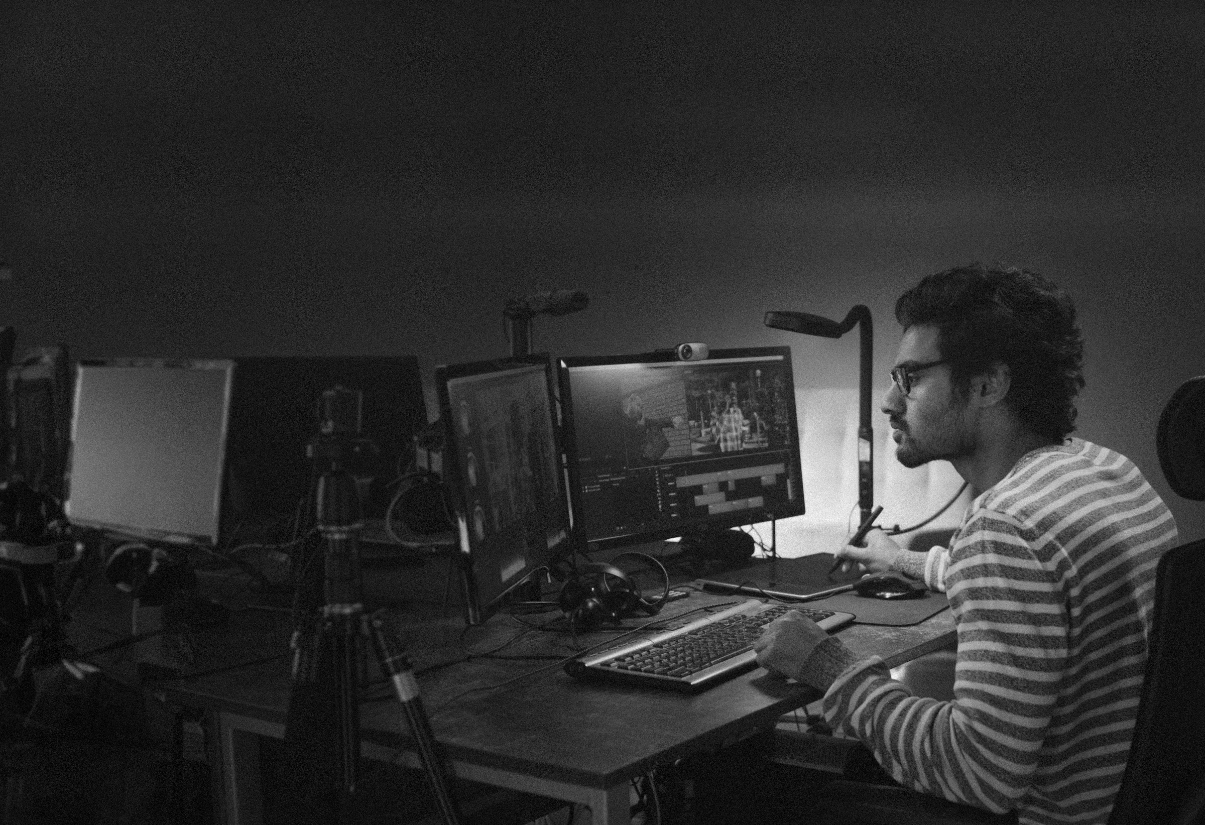Someone editing across several monitors in a dark room
